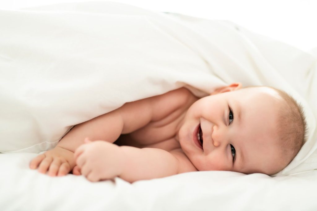 5 Monate altes Baby lächelt im Bett.