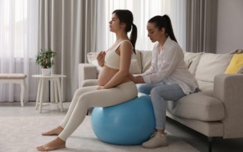 Eine schwangere Frau auf einem Yogaball bei der Geburtsvorbereitung.