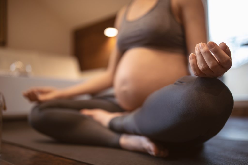Eine schwangere Frau, die sich mit Yoga auf die anstehende Geburt vorbereitet.