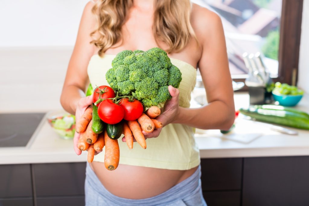 Eine schwangere Frau bereitet sich mit gesunden Lebensmittel auf die Geburt vor.