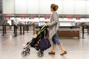 Eine Mutter schiebt ihr Baby im klappbaren Reisebuggy durch den Flughafen.