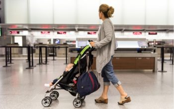 Eine Mutter schiebt ihr Baby im klappbaren Reisebuggy durch den Flughafen.