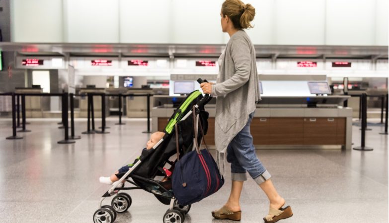 Eine Mutter schiebt ihr Baby im klappbaren Reisebuggy durch den Flughafen.